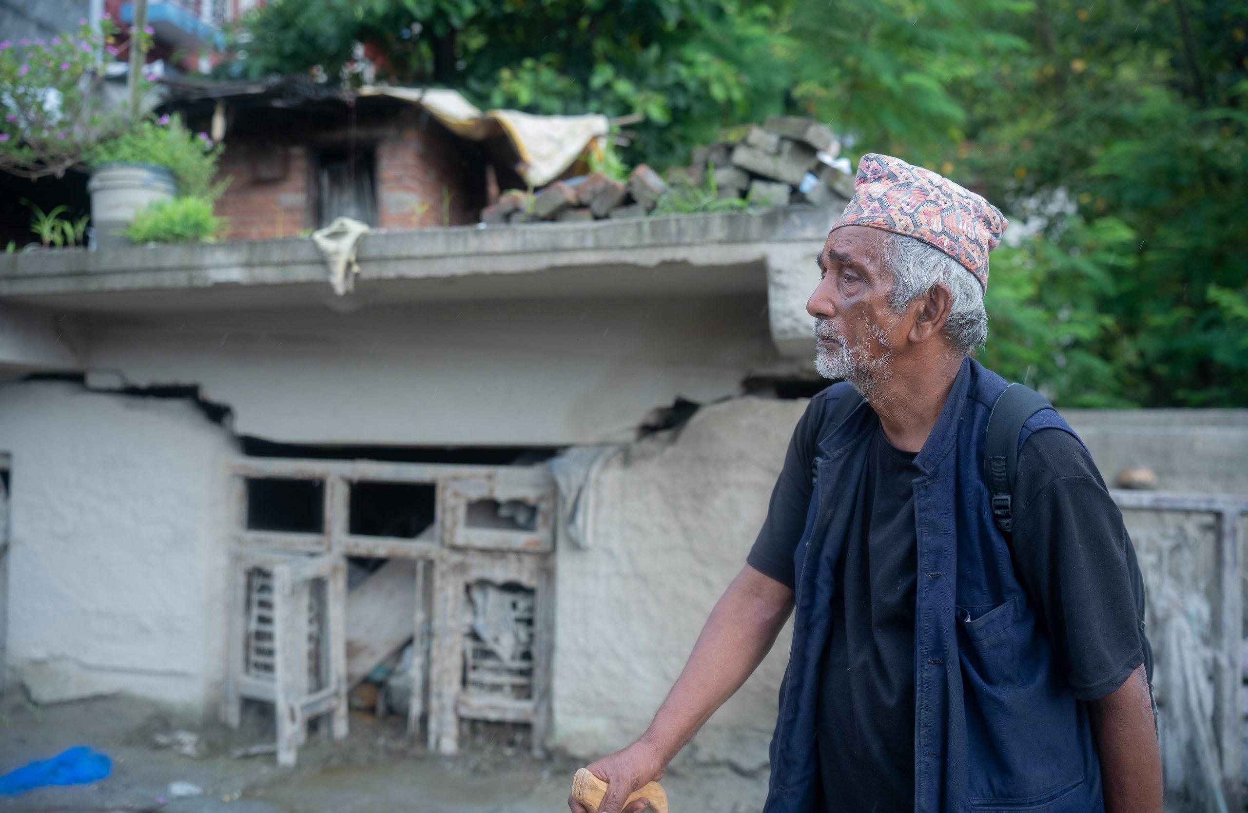 Krishna Bahadur Nepali guarda la sua casa distrutta a Devighat Bazaar, Nuwakot. Foto di Sharada Bashyal / Oxfam